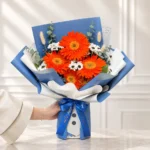 دسته گل اسفنجی ژربرا نارنجی آراد با کرزنتیا و کاغذ ضدآب آبی