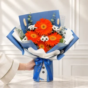 دسته گل اسفنجی ژربرا نارنجی آراد با کرزنتیا و کاغذ ضدآب آبی